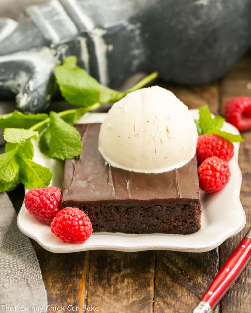 Ice cream topped Fudgy Chocolate Sheet Cake with Cocoa Icing on a white dessert plate.