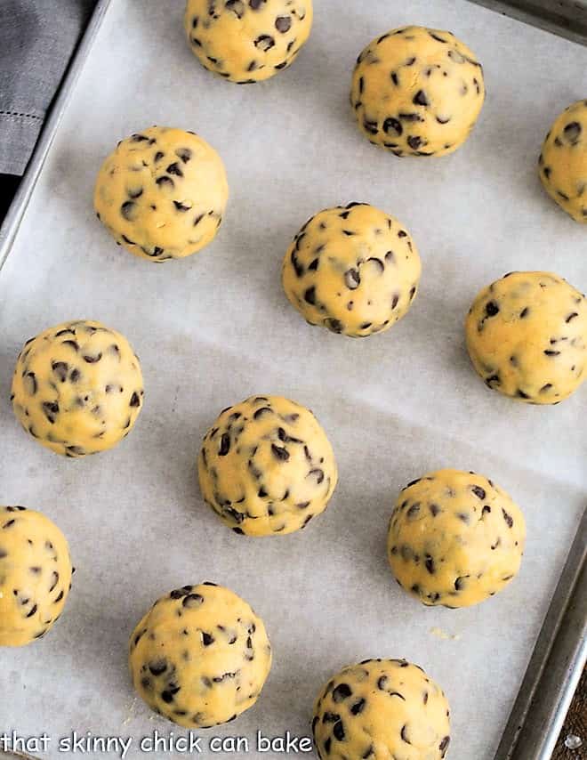 Big Chocolate Chip Cookie Recipe for huge sharable cookies! 12 large chocolate chip cookie dough balls on a sheet pan.