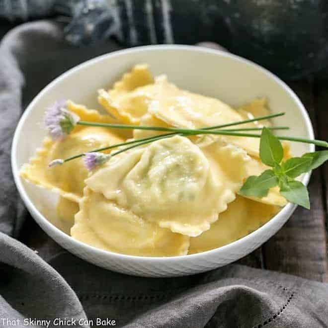 Bowl of Mozzarella, Basil, Parmigiano-Reggiano Ravioli with Butter Sage Sauce garnished with fresh basil and chives.