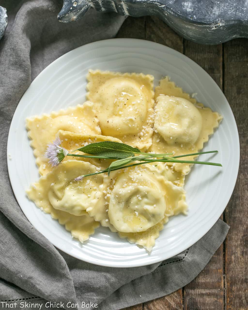 Overhead view of Mozzarella, Basil, Parmigiano-Reggiano Ravioli with Butter Sage Sauce on a white dinner plate.