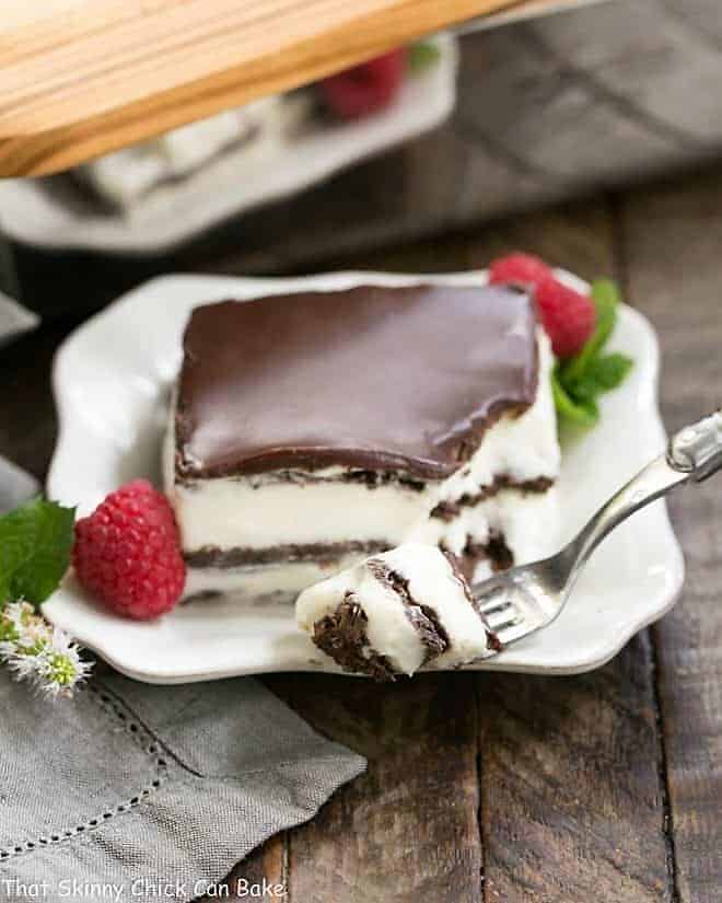 A piece of no bake chocolate lasagna on a plate with a fork with a bite on the tines
