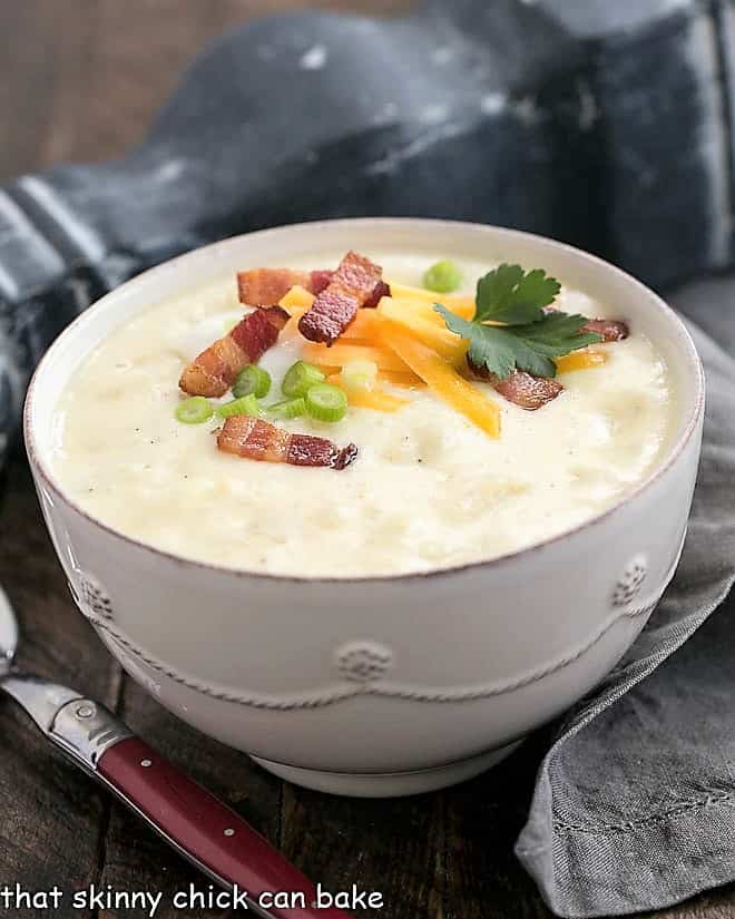 Loaded Baked Potato Soup - Creamy soup with chunks of baked potatoes and topped with cheddar, bacon, sour cream and chives! Loaded Baked Potato Soup in a white terrine garnished with cheese, bacon and chives.