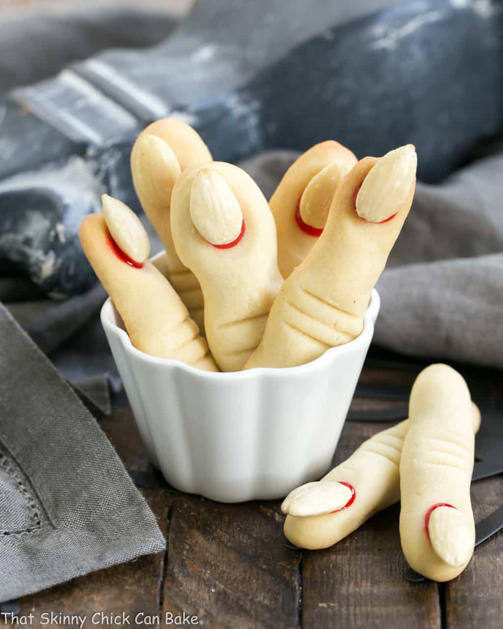 Witches Fingers Cookies - A simple recipe to transform sugar cookie dough into gnarly fingers for Halloween! Witches Fingers Cookies standing upright in a white ramekin.
