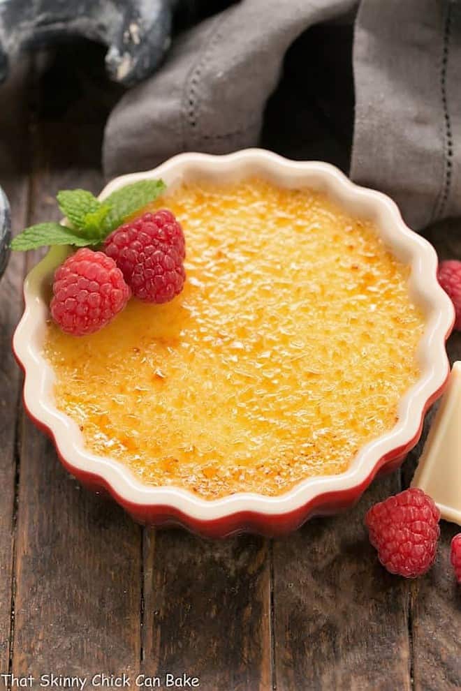 White Chocolate Crème Brûlée - An ultra creamy custard infused with white chocolate and topped with burnt sugar White Chocolate Crème Brûlée in a red ramekin.