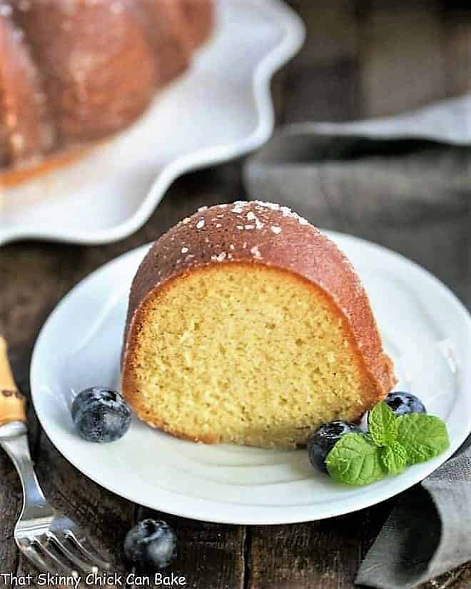 Kentucky Butter Bundt Cake slice on a white dessert plate garnished with blueberries and a sprig of mint