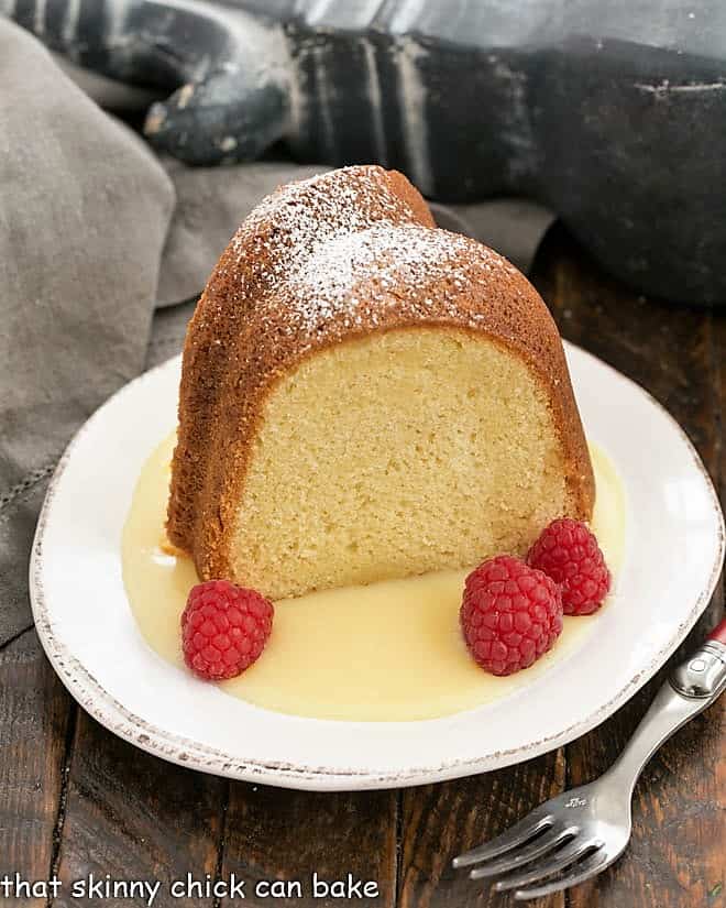 White Chocolate Bundt Cake Flavored with vanilla and a touch of almond, this glazed Bundt cake is a winner! Slice of white chocolate pound cake on a dessert plate with raspberries and white chocolate sauce.