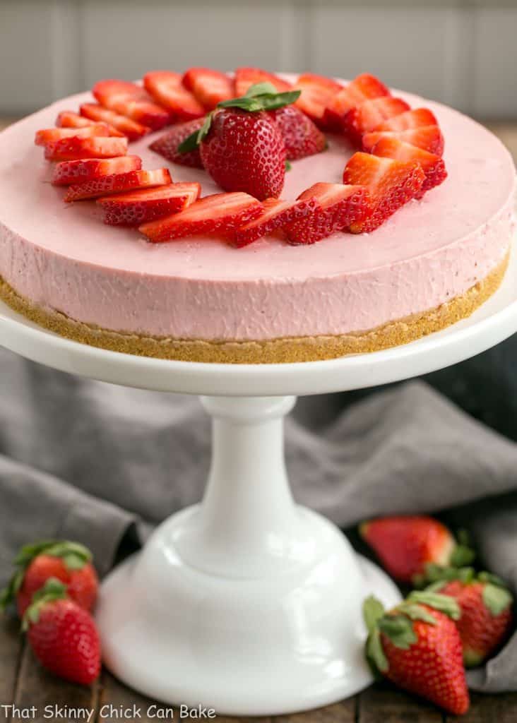 No-Bake Strawberry Cheesecake on a white ceramic cake stand