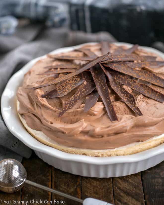 Chocolate Velvet Pie with Meringue Crust in white pie plate topped with chocolate shards and dusted with cocoa powder