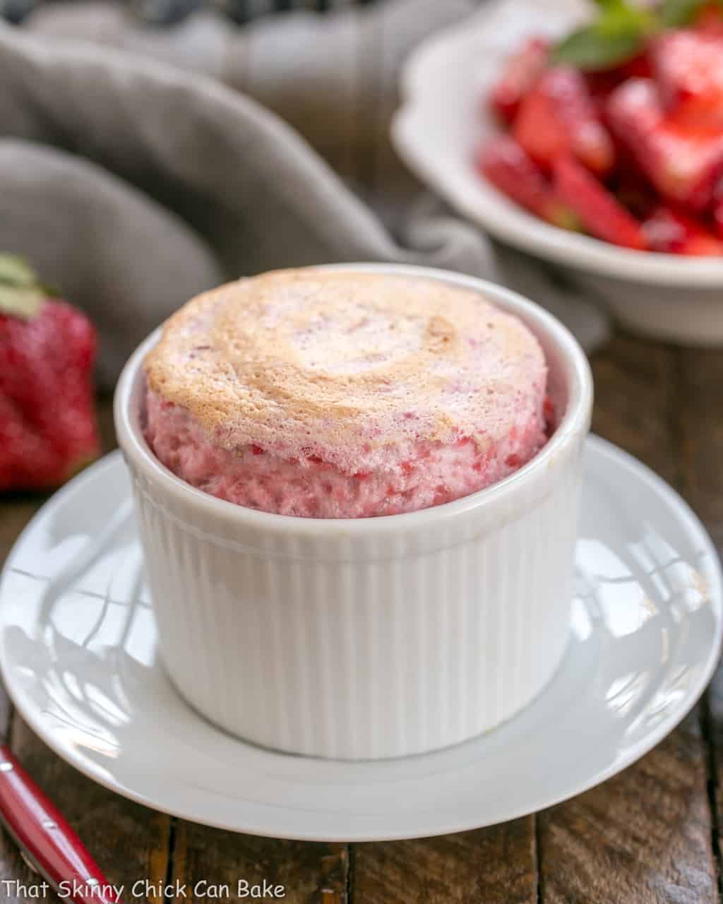 Strawberry Soufflés with Fresh Strawberries | An elegant berry dessert you can make at home! A baked strawberry souffle fresh out of the oven on a white plate.