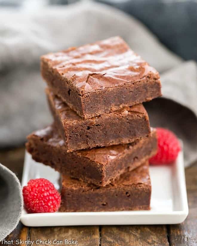 Best Fudgy Brownies stacked on a white square plate.