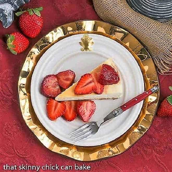 Mascarpone Cheesecake with Balsamic Strawberries - The most creamy, luscious cheesecake topped with sweetened balsamic strawberries Italian Cheesecake with Balsamic Strawberries overhead view on a white plate over a gold charger plate.