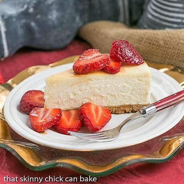 Italian Cheesecake with Balsamic Strawberries - The most creamy, luscious cheesecake topped with sweetened balsamic strawberries Mascarpone Cheesecake with Balsamic Strawberries on a white dessert plate with a red handled fork.