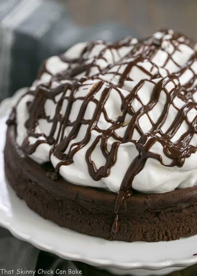 Flourless Chocolate Cake with Marshmallow Frosting on a white cake stand.