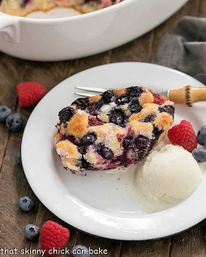 Easy Mixed Berry Cobbler - a simple, delicious dessert make with seasonal berries A serving of Easy Mixed Berry Cobbler on a white dessert plate with a scoop of ice cream and fresh berries.