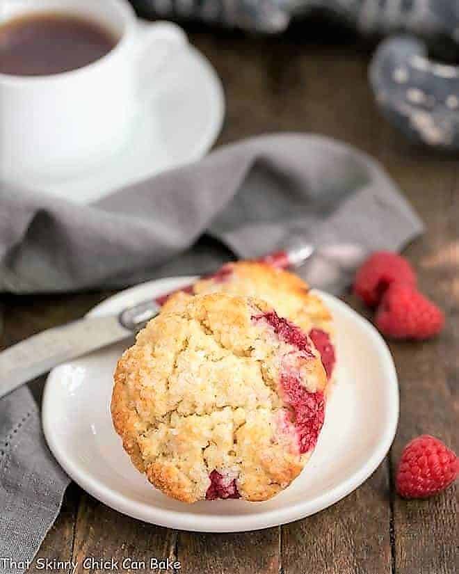 Raspberry Cream Scones - terrific, tender scones studded with fresh raspberries Raspberry Cream Scones on a round white plate with a cup of tea.