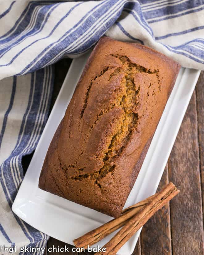 Overhead view of Pumpkin bread on a white tray with cinnamon sticks.