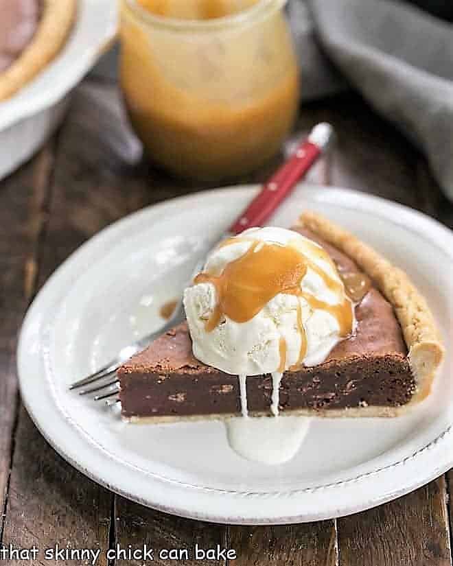 Fudgy Brownie Pie - Rich brownie filling studded with chocolate chips and baked in a flaky pastry shell! A slice of Fudgy Brownie Pie topped with ice cream and caramel sauce.