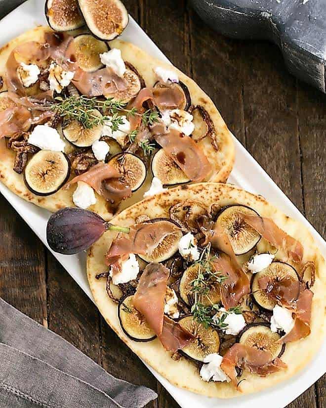 Fig, Goat Cheese and Prosciutto Pizza on a white platter with fresh figs.