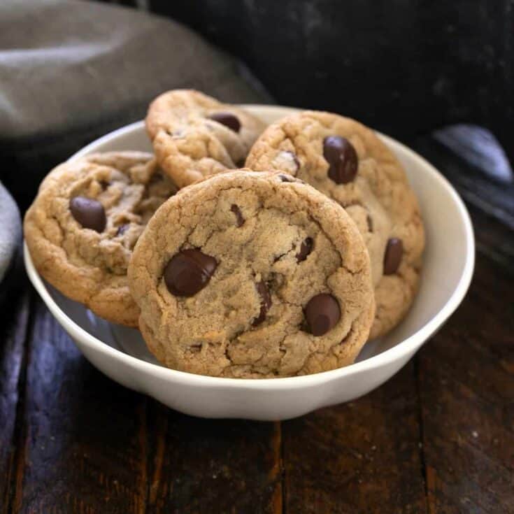 4 killer chocolate chip cookies in a small white bowl.
