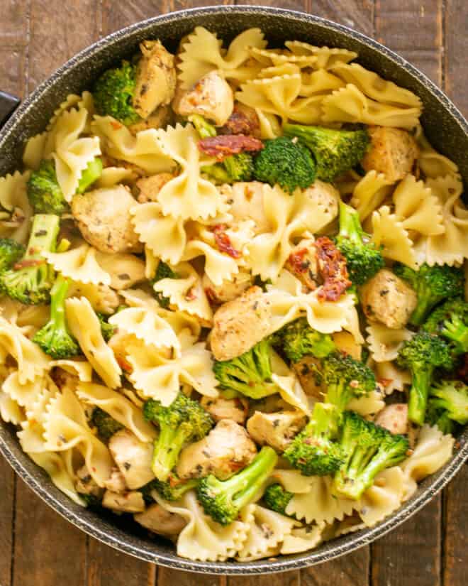 Chicken in skillet with broccoli and pasta.