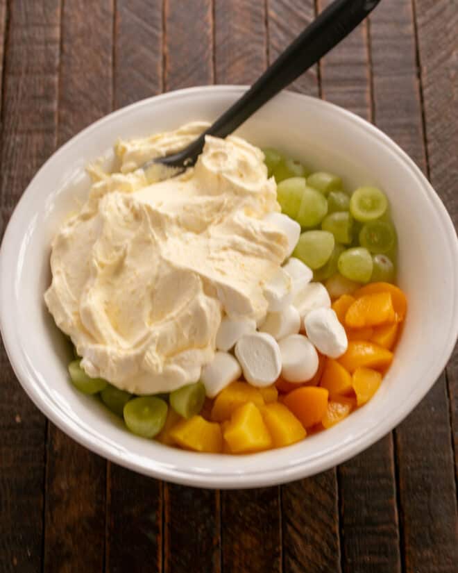 Adding whipped cream dressing to fruit.