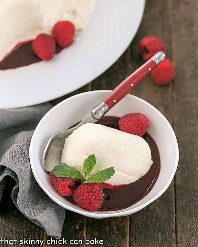 Coeur a la Creme - An exquisite no-bake dessert that's perfect for for cheesecake lovers! Serving of no bake cheesecake in a bowl with fresh raspberries and mint.