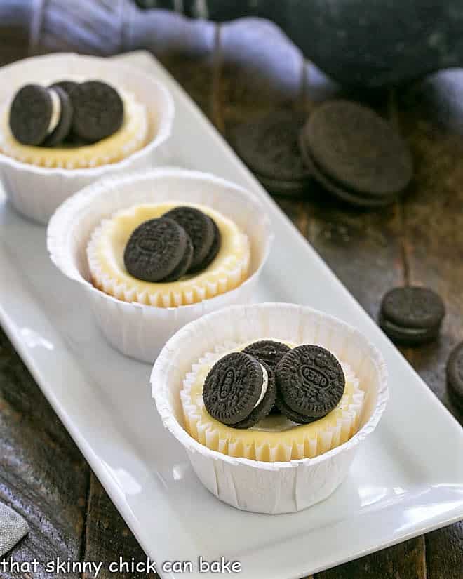 Mini Oreo Cheesecakes lined up on a white rectangular platter.