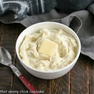 Bowl of cream cheese mashed potatoes in a white bowl with a pat of butter
